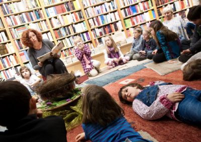 Kinder lauschen einer Lesung auf buntem Teppich