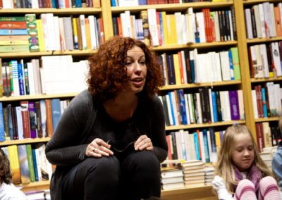 Ulrike Motschiunig erzählt gespannt vor Bücherregal