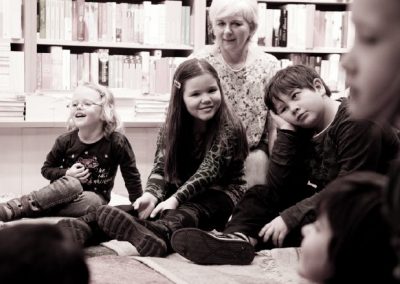 Kinder lachen bei Vorlesestunde mit Betreuerin