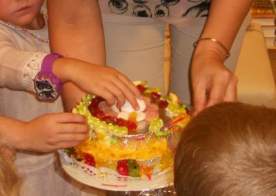 Kinder dekorieren gemeinsam bunten Obstkuchen